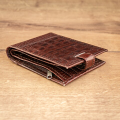 Brown leather wallet on a wooden background. Close-up.