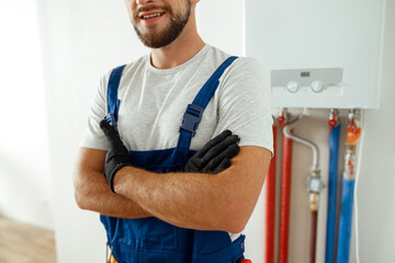 Cropped shot of smiling technician installing and setting the new gas boiler for hot water and...