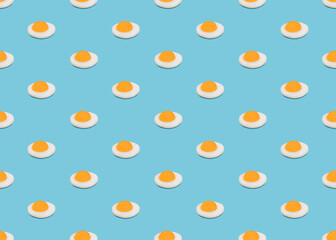 Seamless pattern with fried eggs. Many very small omelets on blue background