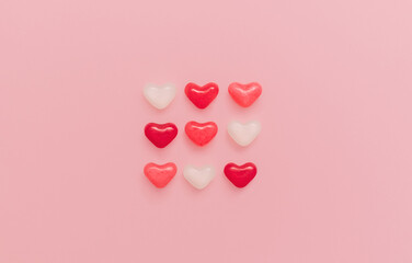 Sweet hearts. Top view photo in minimal style. Colorful marmalade in heart shape on pink backdrop