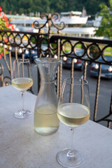 Tasting of white quality riesling wine served on outdoor terrace in Mosel wine region and old German town on background, Germany