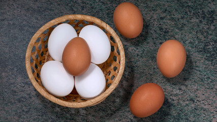 several fresh chicken eggs in a straw basket on a wooden background. Healthy eating concept.