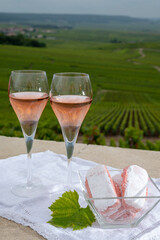 Symbols of Reims, rose brut champagne wine and rose biscuits and view on green pinot noir grand cru vineyards of famous champagne houses in Montagne de Reims near Verzenay, Champagne, France