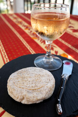 Taste of Provence, small round cheese Tome de Provence made from goat milk in Banon, Alpes-de-Haute-Provence, France served with glass of cold rose wine