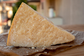 Cheese collection, piece of matured cow cheese pasmesan parmigiano reggiano and Italian houses on background