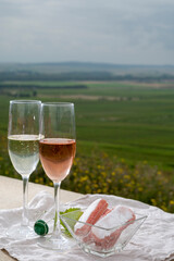 Symbols of Reims, white and rose brut champagne wine and rose biscuits and view on green pinot noir grand cru vineyards of famous champagne houses in Montagne de Reims near Verzenay, Champagne, France