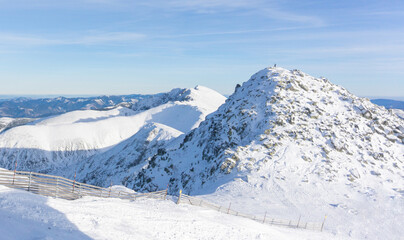 Fototapeta na wymiar Valley of hilghland mountain winter resort on bright sunny day. Panoramic wide view of downhill slopes