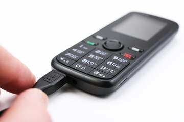 Retro mobile phone while charging. On white background. 