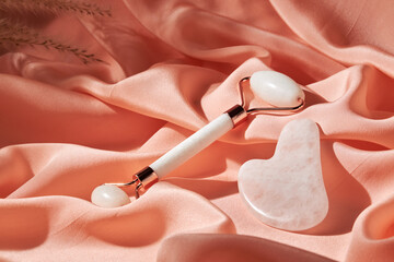 Massage quartz Jade roller and Gua Sha  tool on a silk cloth. Facial kit for home skin care and spa