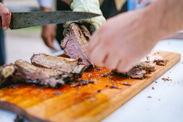 Manos de cerca cortando costillar a la llama de ternera