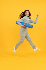 Fototapeta na wymiar positive child in sportswear running with fitness mat. fit your body. sport teen girl training