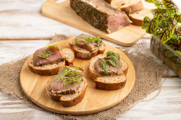 Bread sandwiches with jerky salted meat, sorrel and cilantro microgreen on white. side view, close up.