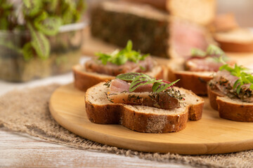 Bread sandwiches with jerky salted meat, sorrel and cilantro microgreen on white. side view, selective focus.
