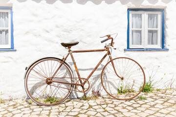 an old rusty bicycle in front of a white house
