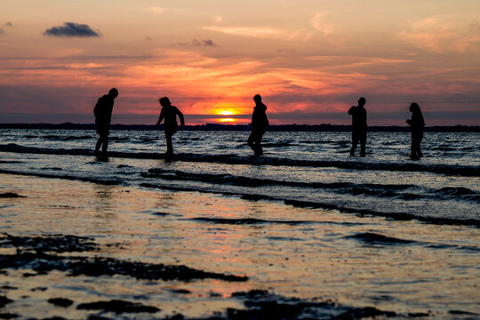 Famille les pieds dans l'eau au soleil couchant