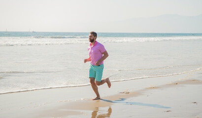 happy man runner running barefoot on summer beach, activity