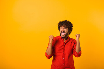 Extremely excited overjoyed man with beard shouting making yes gesture, amazed with his victory, triumph. Indoor studio shot isolated on yellow background