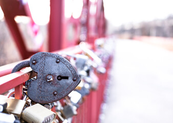 Closeup heart shape of vintage rusty steel padlock hold at the red bridge, depth of field. Traditional symbol for strengthen, loyalty, forever mutuality and eternity love of couple. Valentine concept.