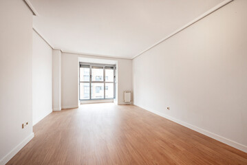 Empty living room with big window in the background, wooden floors and white painted walls
