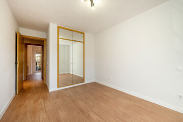Fototapeta premium Room with built-in wardrobe with doors covered with mirrors and white painted walls