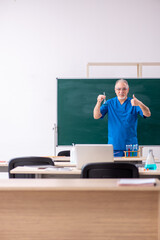 Old male teacher chemist in the classroom