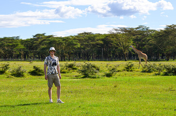 A man in a cap and a floral shirt is posing with a giraffe, safari, Naivasha Park, Kenya, Africa