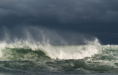 Obraz premium Seascape. Powerful ocean wave on the surface of the ocean. Wave breaks on a shallow bank. Stormy weather, stormy clouds sky background.