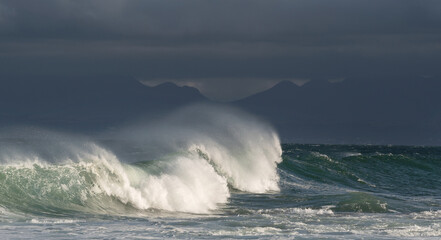 Seascape. Powerful ocean wave on the surface of the ocean. Wave breaks on a shallow bank. Stormy weather, stormy clouds sky background.