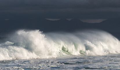 Obraz premium Seascape. Powerful ocean wave on the surface of the ocean. Wave breaks on a shallow bank. Stormy weather, stormy clouds sky background.