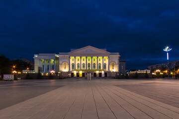 Fototapeta na wymiar Beautiful view of the illuminated building of the Tyumen Big Drama Theater and the Square of the 400th Anniversary of Tyumen at twilight, Russia 