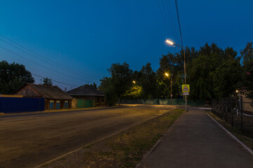 Perspective view of the illuminated Bazhova Street at twilight in summer, Kurgan, Russia
