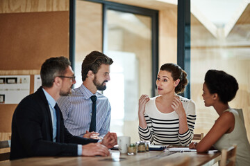 Planning session in progress. Portrait of a group of colleagues talking together around a table in an office.