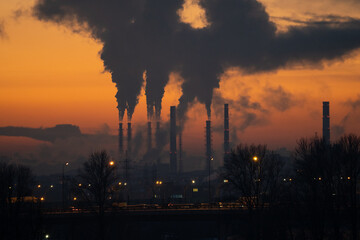 Winter industrial landscape. Coal-fired power station with smoking chimneys against dramatic sunset...