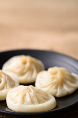 Xiao long bao, small Chinese steamed bun filling with minced pork on black plate