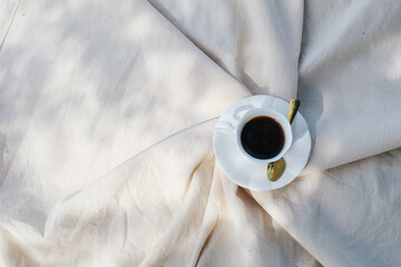 Hot Coffee in white cup on picnic blanket morning light background relaxing on holiday. Sunrays. Still life concept. Copy space. Colorful autumn picnic