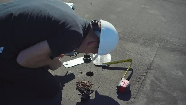 Roofing Inspector performing a core test on a flat roof on a sunny day