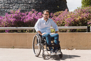 Latino adult man in a wheelchair in a park looking at the camera