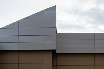 The exterior wall of a contemporary commercial style building with aluminum metal composite panels and glass windows. The futuristic building has engineered diagonal cladding steel frame panels.