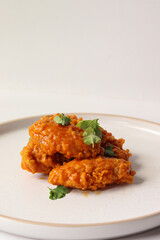spicy buffalo wing on a plate served gourmet decorated with coriander leaves