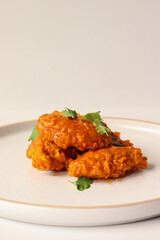 spicy buffalo wing on a plate served gourmet decorated with coriander leaves