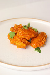 spicy buffalo wing on a plate served gourmet decorated with coriander leaves