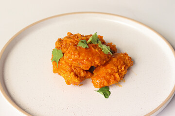 spicy buffalo wing on a plate served gourmet decorated with coriander leaves