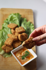woman's hand holding a chicken nuggets at lunch, with ketchup and spicy buffalo sauce