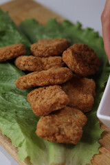 woman's hand holding a chicken nuggets at lunch, with ketchup and spicy buffalo sauce