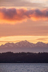Colorful clouds and an overcast sky at sunset with the ocean in the foreground and mountains in the background
