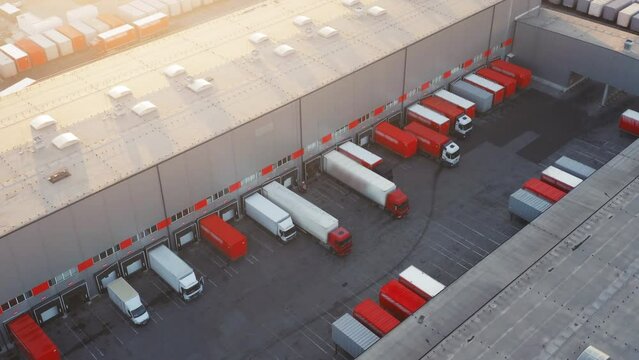 Aerial view of a warehouses in a logistics park with many semi-trailers trucks standing at rumps for loading and unloading goods