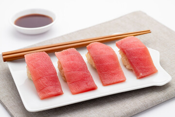 Toro nigiri sushi or tuna nigirizushi, seasoned cooked Japanese rice, Kome, with toppings of slices of belly loins of the fresh raw fatty tuna, served on the rectangle white plate. 