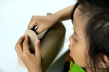Close-up of little girl assembling box craft. Eco-friendly disposable paper. Fast food container