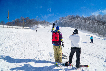 Two snowboarders snowboarding in mountain. Snowboarders enjoying leisure activities on outdoors. Group of friends enjoying the winter season in winter forest.
