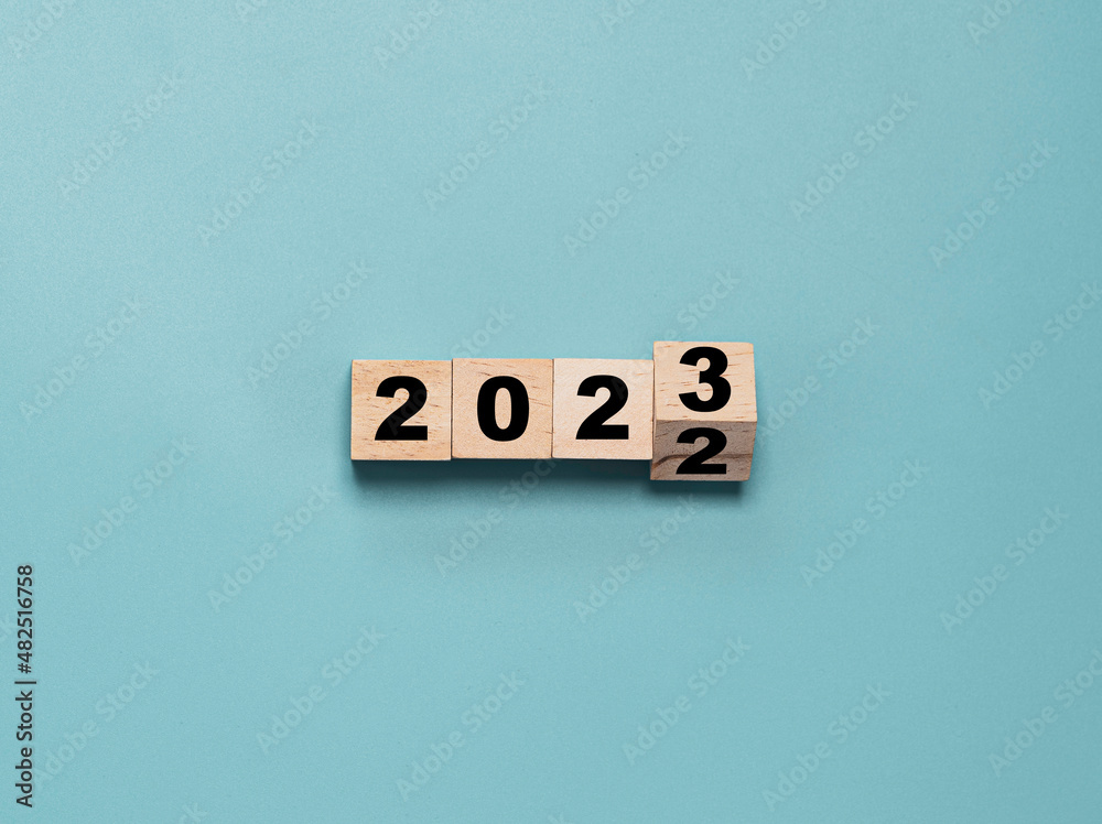 Wall mural Wooden block cube flipping between 2022 to 2023 for change and preparation merry Christmas and happy new year.